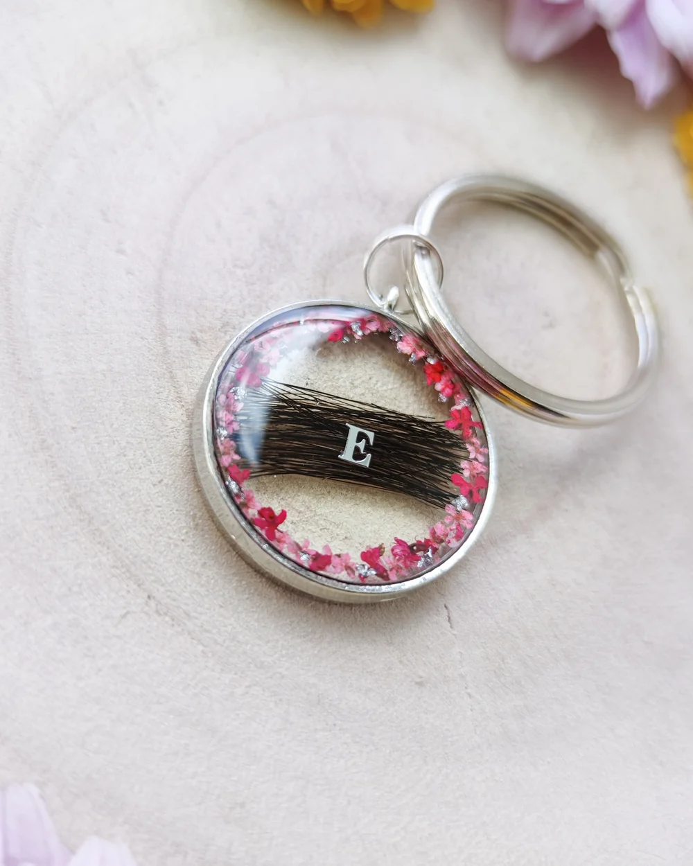 Porte-clés souvenir en résine avec une mèche de poils, un prénom et des fleurs séchées